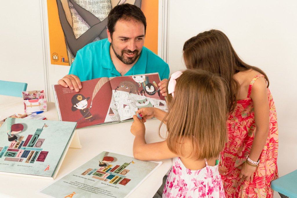 Dos niñas escuchan el cuento Menudo Castillo en la Feria del Libro de León